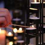 Hands light a candle at a station like those set up during worship at CRCC